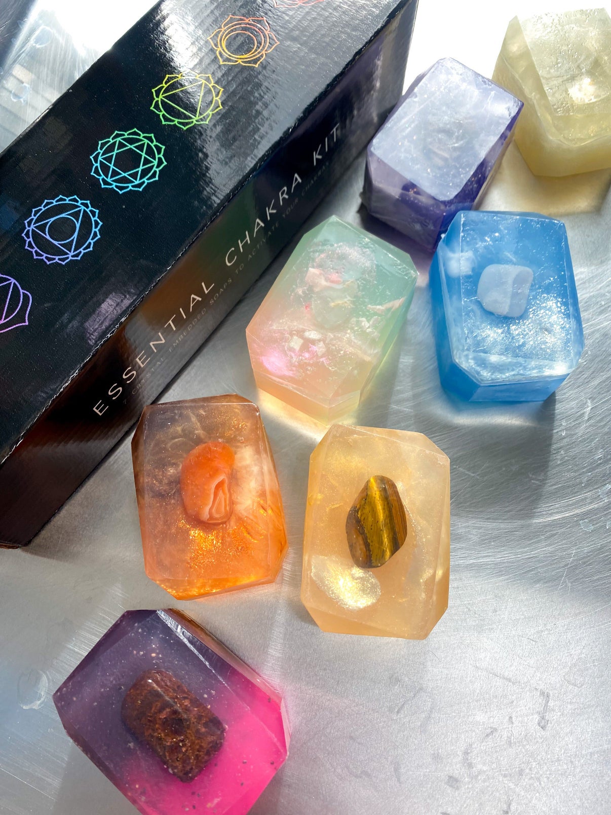 seven bars of different colored soaps with crystals in their centers