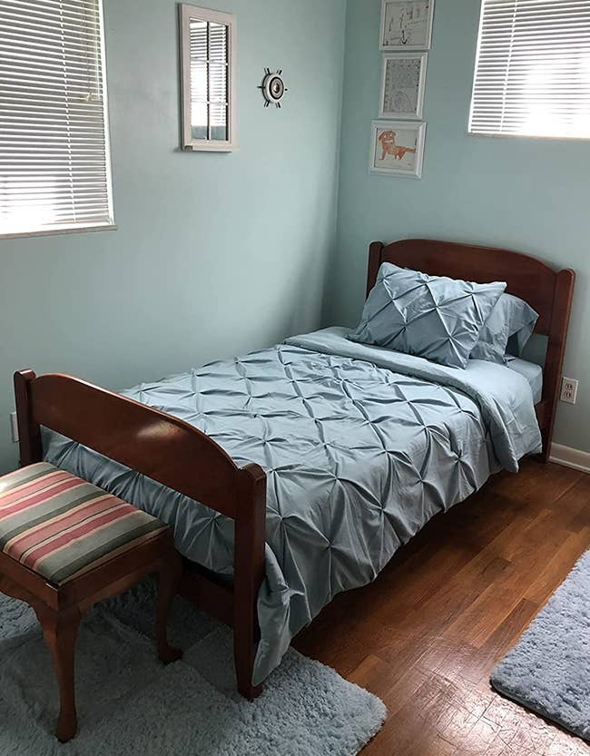 Reviewer image of teal pleated twin-size comforter set with matching sham on a dark wooden bed frame