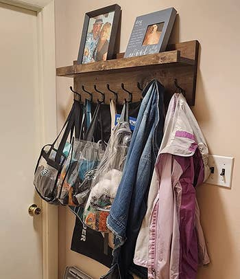 reviewer photo of the wooden coat rack holding jackets and bags