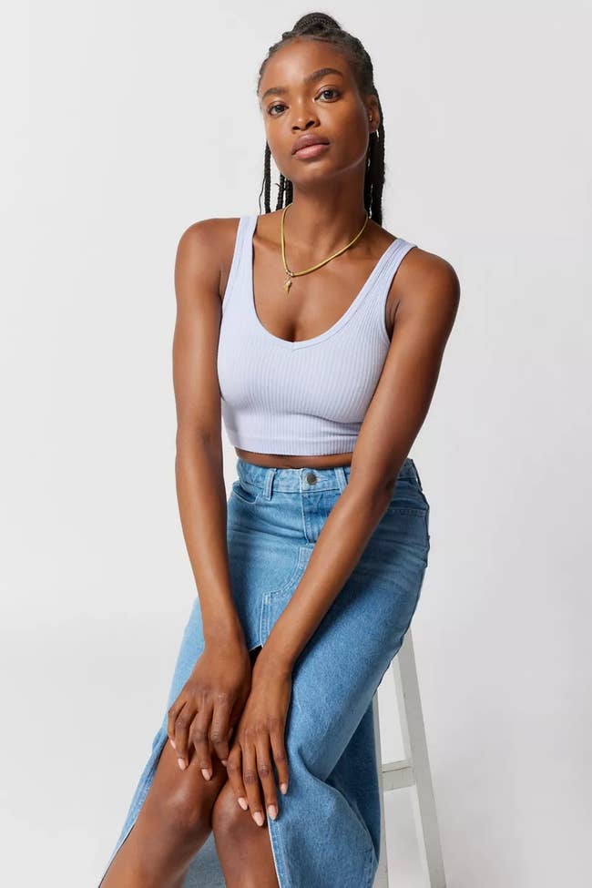 A model posing in the periwinkle top and a denim skirt