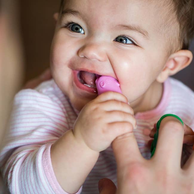 a child chewing on the pink silicone brush