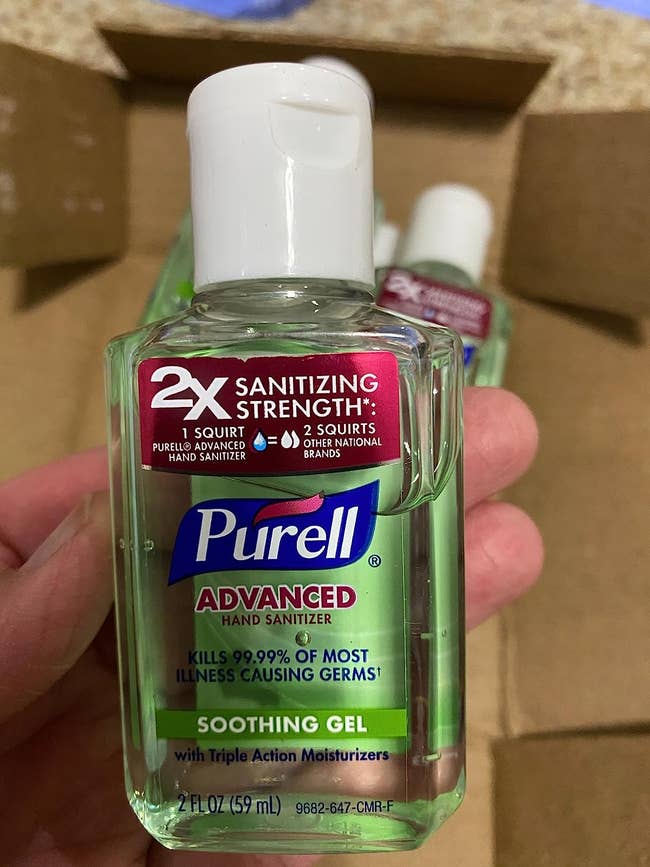 Reviewer holding travel size Purell hand sanitizer