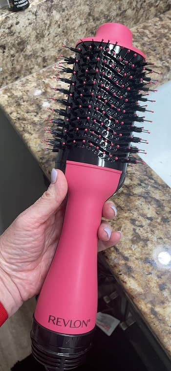 A reviewer holding the hair dryer brush in their hand