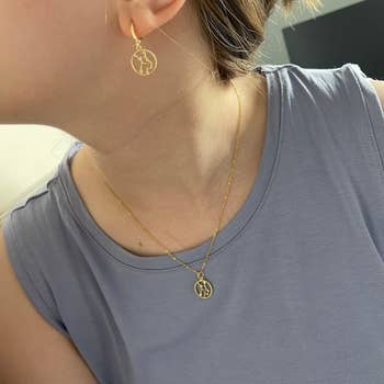 person wearing a gold zodiac themed necklace