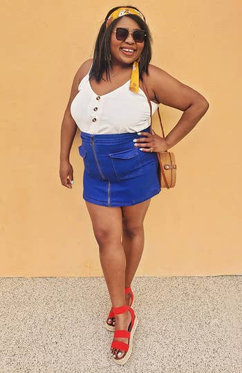 reviewer wearing the white top with a blue skirt and red sunglasses