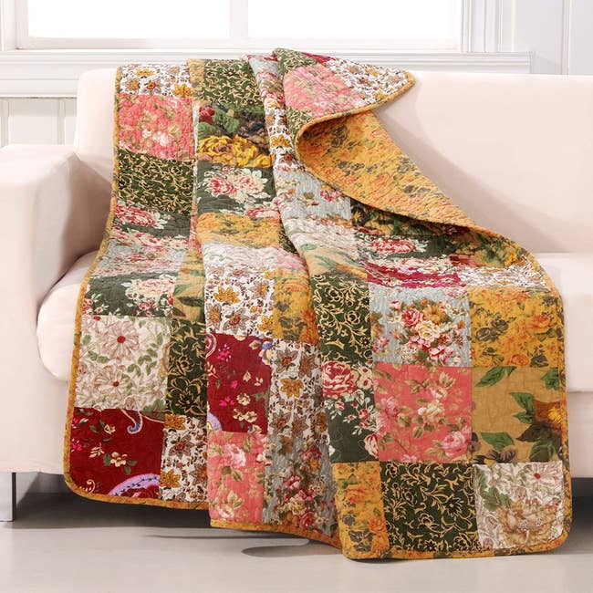 A patchwork floral quilt laid out on a sofa 