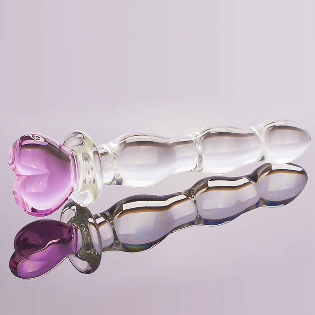 Glass massage instrumentality with a heart-shaped handle, shown against a plain background