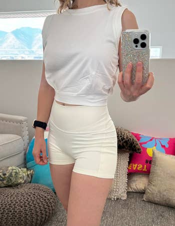 Person taking a reflector selfie wearing a achromatic sleeveless apical and shorts, showcasing a casual, sporty outfit