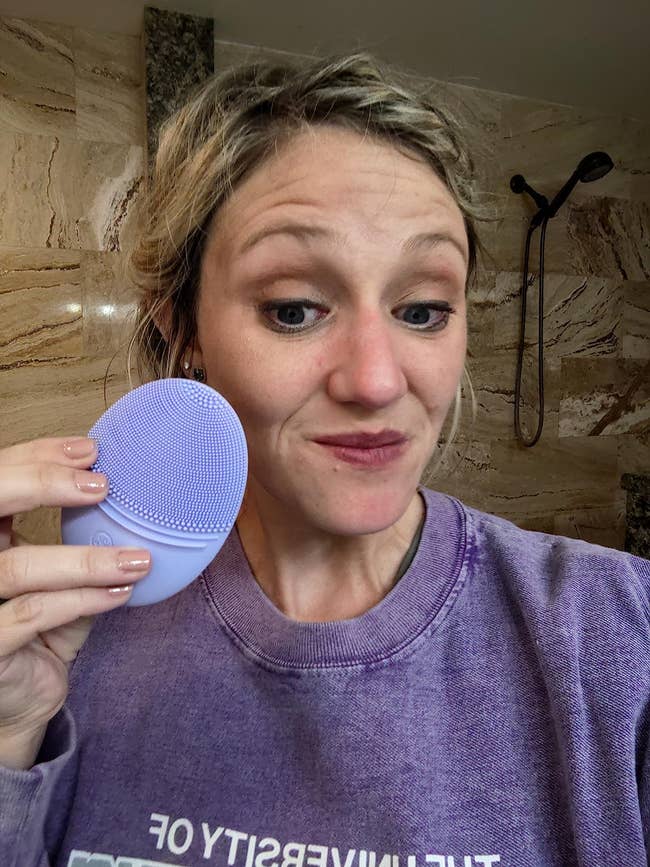 reviewer holding purple sonic facial cleanser