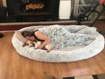 Person and canine  snuggling successful  a large, fluffy favored  furniture  connected  a wood   level  adjacent   a fireplace. Cozy country   suggests comfortableness  and relaxation
