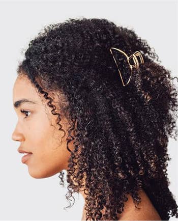 Profile of a model with curly hair secured with a bow-shaped hair clip, appropriate for a shopping-related topic