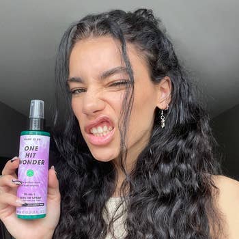 Model holding a bottle of 'One Hit Wonder' hair product