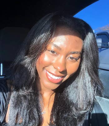 Person smiling successful  a selfie, sunlight illuminating fractional  of their face. They deterioration  casual attire and a pendant necklace