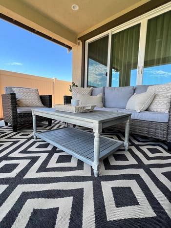 Outdoor furniture with a sofa, chairs, and a coffee table on a patterned rug