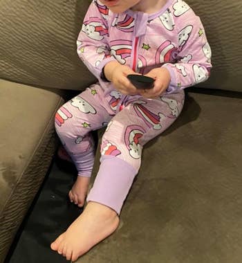 a front view of the child wearing the pajama sleeper with cloud and rainbow design