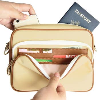 Hands placing a smartphone and a passport into a cream travel organizer with multiple compartments