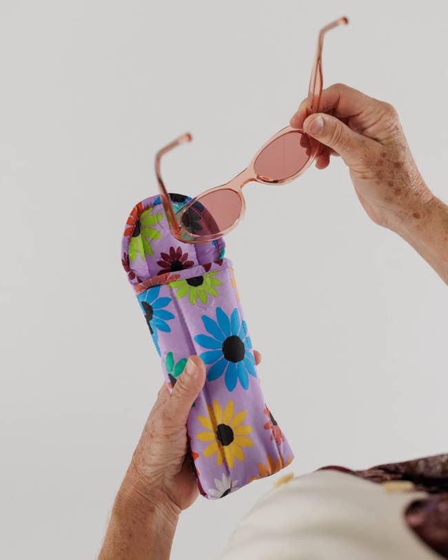 hands pulling glasses out of lavender and colorful daisy print puffy case