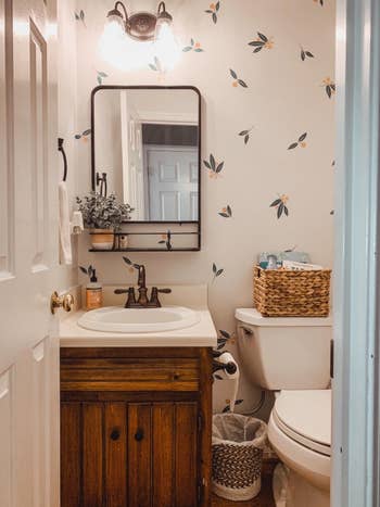 reviewer photo of their bathroom with the tangerine wall decals on the back wall