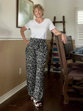 Person in a white tee and patterned pants, standing casually in a home setting