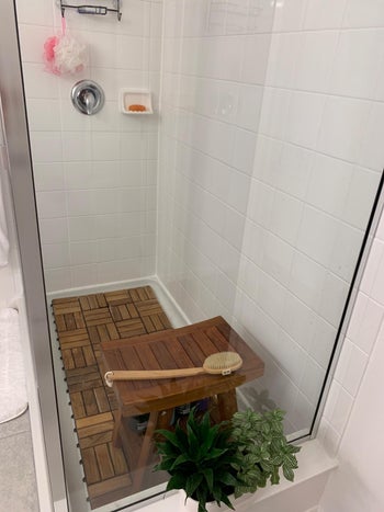 same teak tiles in shower with glass doors and small bench