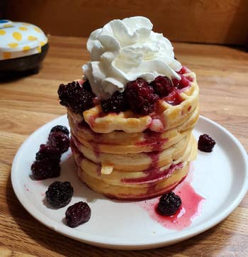 stack of waffles with whipped cream and blackberries