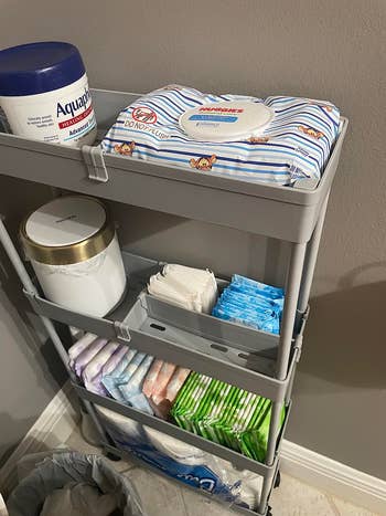Storage cart with babe wipes, ointment, napkins, and diapers organized connected shelves, illustrating a applicable setup for babe attraction essentials