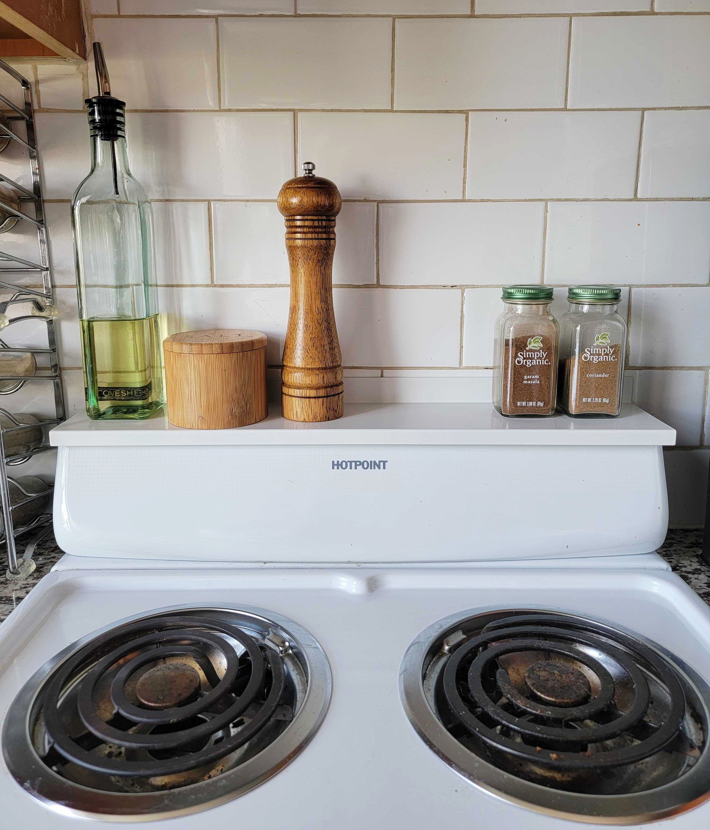 A clean stove with condiments and oil bottles on the stove shelf