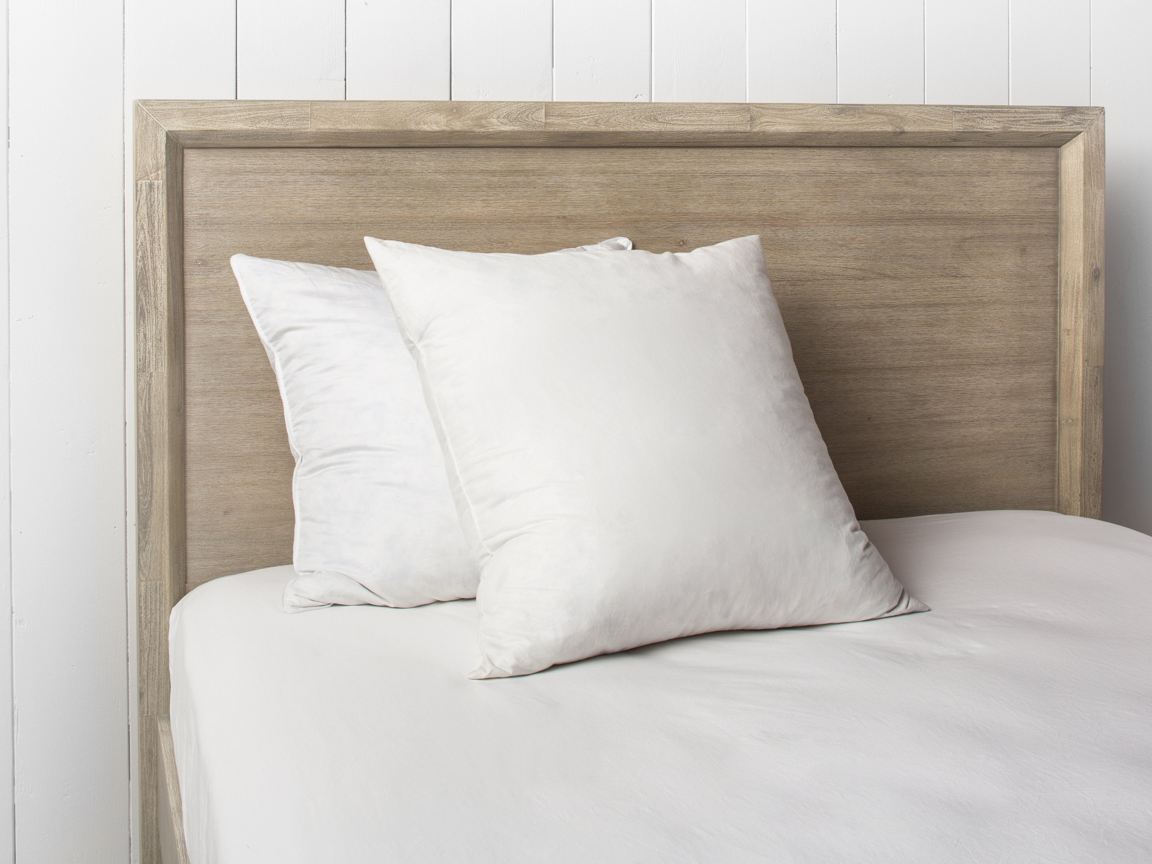 Two square white pillows on a bed