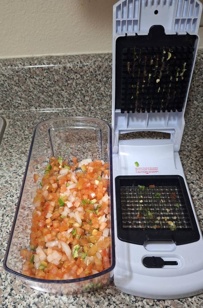 Vegetable dicer with chopped tomatoes, onions, and herbs successful the container