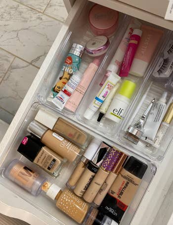 Makeup stacked and organized in clear rectangular containers in a drawer 