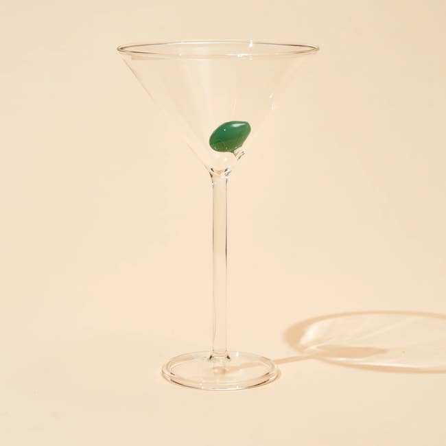 martini glass with green olive at the bottom