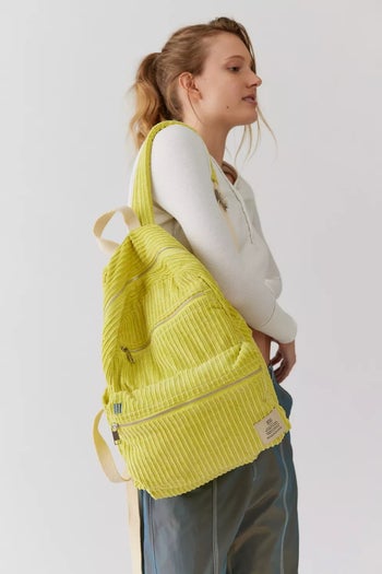 A model wearing the chartreuse corduroy backpack