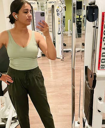reviewer wearing light green longline sports bra with joggers at gym