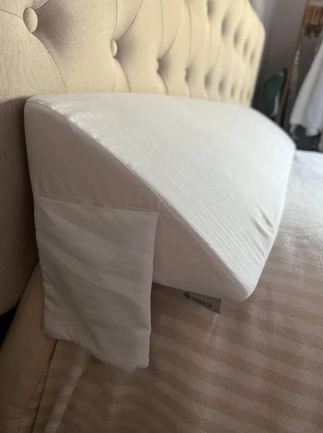White triangle shaped pillow that takes up the length of the top of a reviewer's bed 