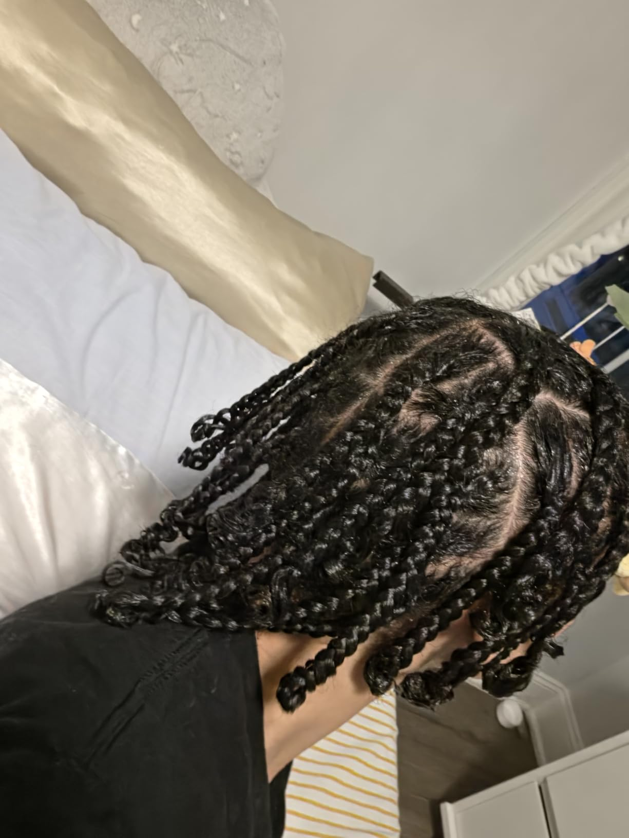 Person with braided hairstyle sitting connected  a bed