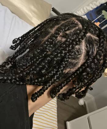 Person with braided hairstyle sitting connected a bed
