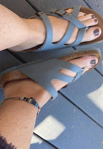 Person wearing blue strapped sandals and multicolored ankle bracelet