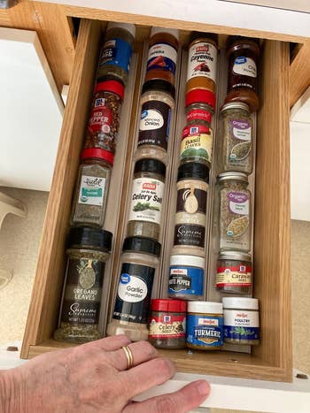 A well-organized room  drawer filled with assorted  spice jars, including ail  powder, turmeric, and oregano, arranged neatly for casual  access