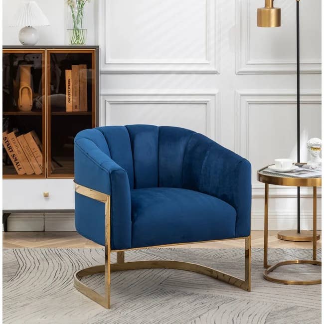 the blue velvet barrel chair next to a side table