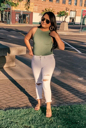 different reviewer wearing the green bodysuit tank tucked into white jeans