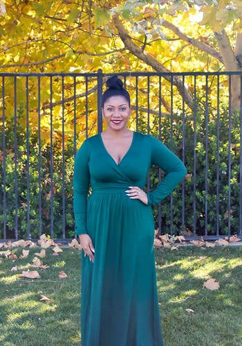 Reviewer wearing dark green long sleeve v-neck maxi dress outside in front of black metal fence