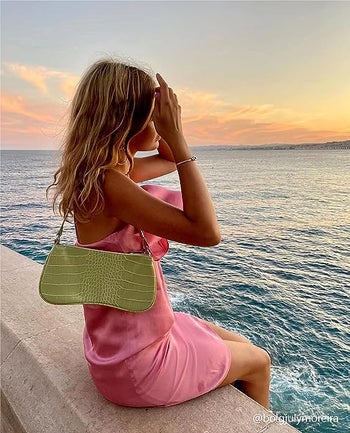 person wearing a green croc-embossed vegan leather purse