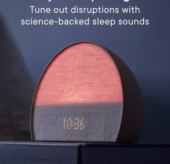 An alarm clock glowing soft red light with a fabric-covered digital display showing the time 