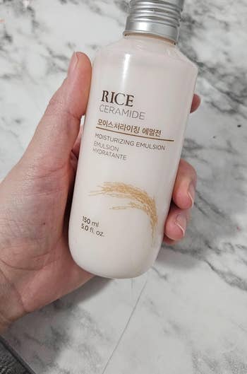 Hand holding a bottle of Rice Ceramide Moisturizing Emulsion skincare product