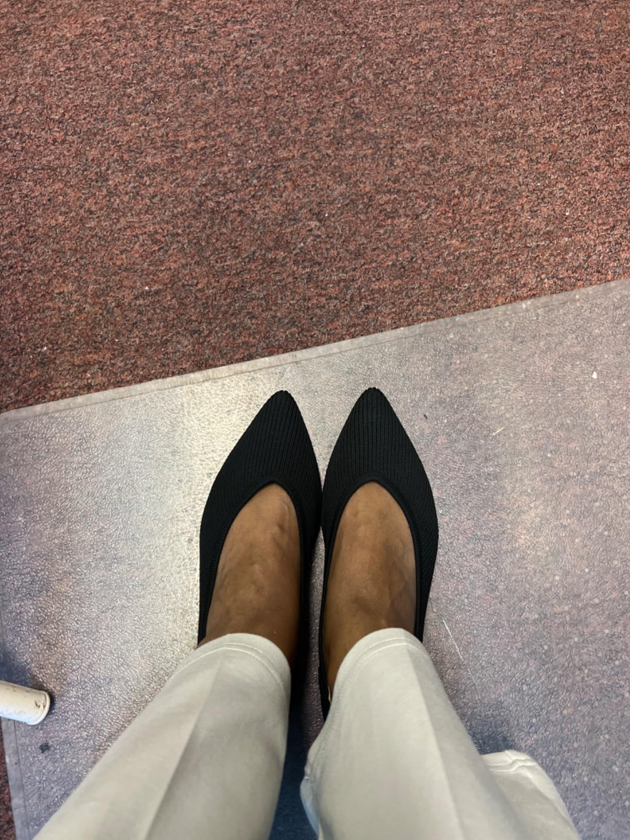 Person wearing achromatic  pointed-toe heels paired with light-colored pants connected  a textured surface