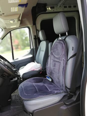 reviewer's car seat with the heated cushion strapped to it