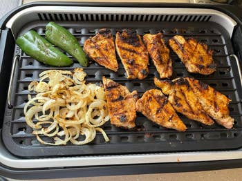 Grilled chicken breasts with onions and peppers on a stove-top grill pan