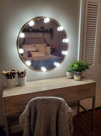 a reviewer's circular vanity mirror with the bulbs surrounding it
