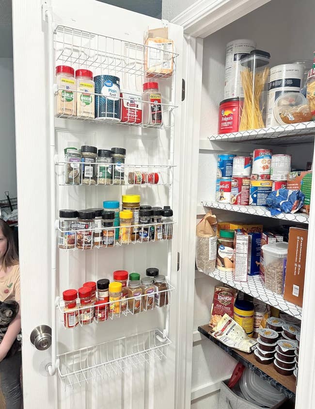 A reviewer's open pantry door with mounted racks holding spices and assorted food items