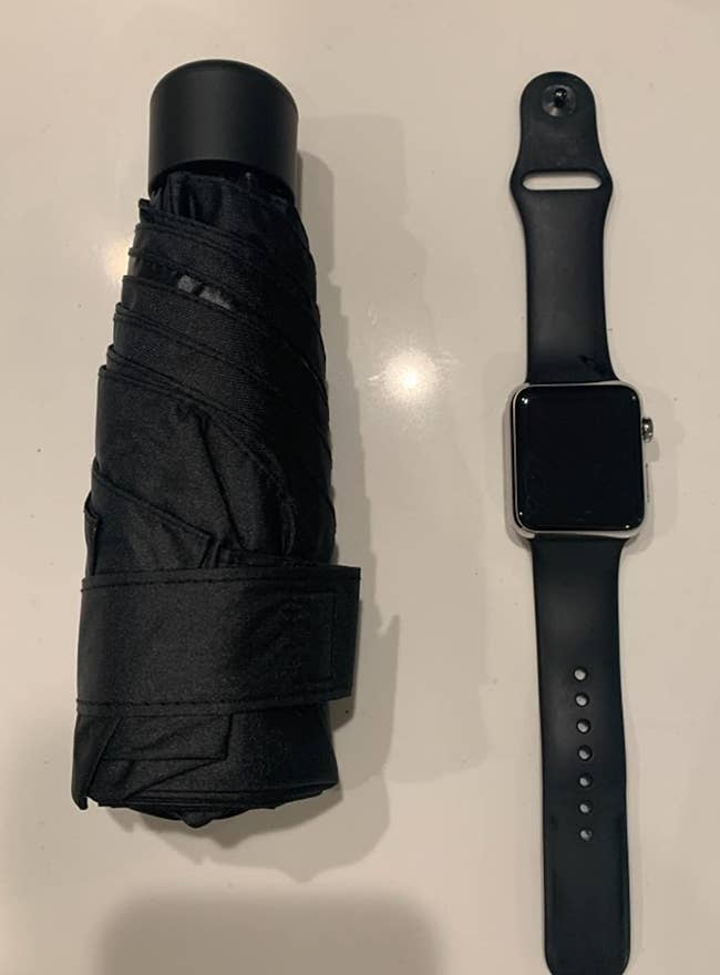 a reviewer photo of the umbrella next to a smart watch strap for scale 